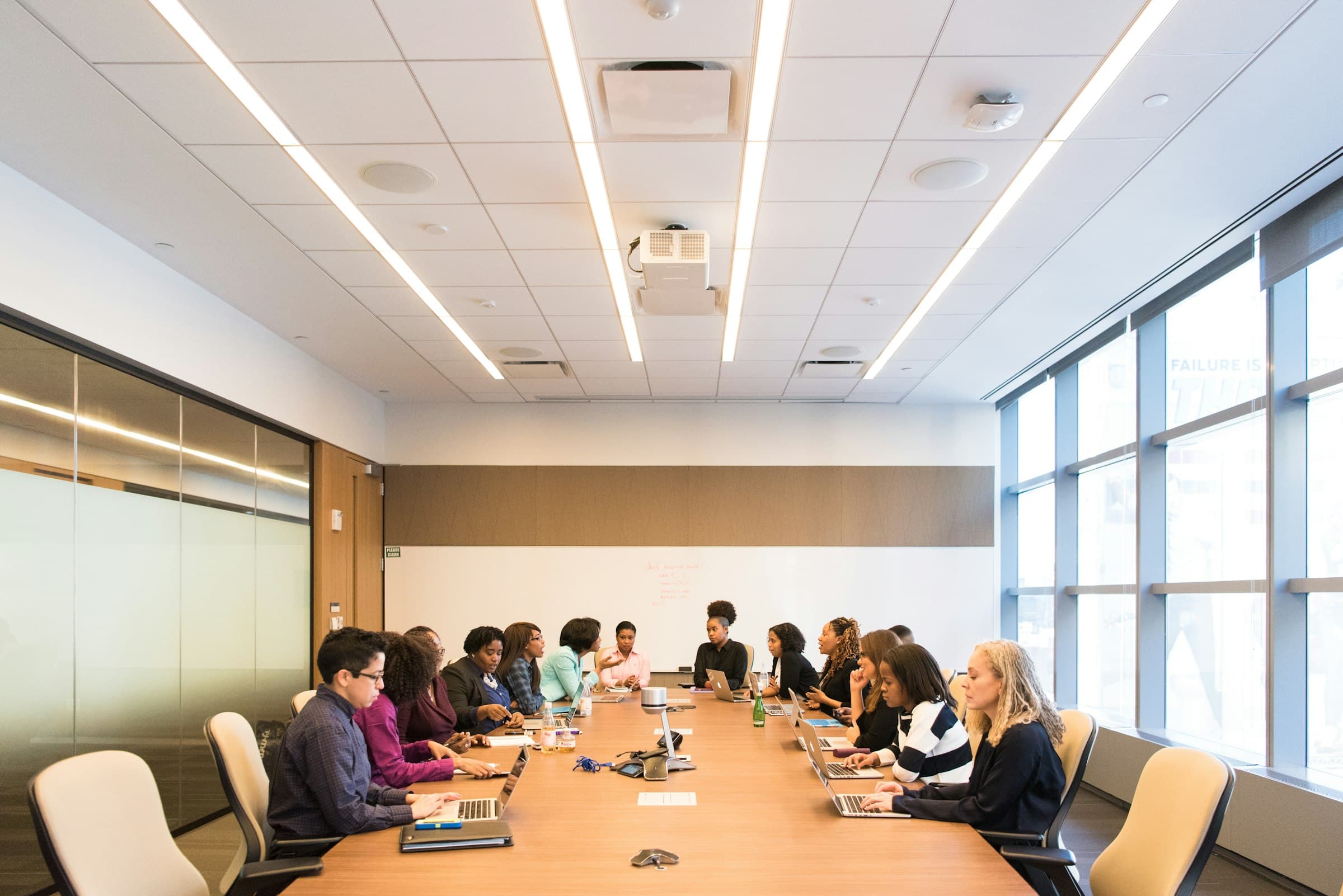 Sesión de trabajo en una sala de juntas con luz natural y equipo profesional reunido alrededor de la mesa.