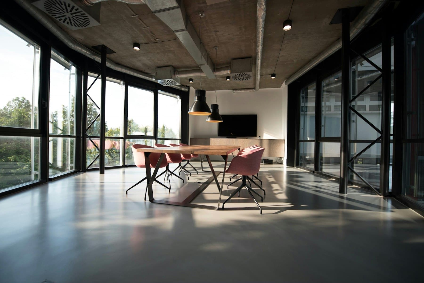 Sala de reuniones vacía con ventanales de piso a techo y luz natural.